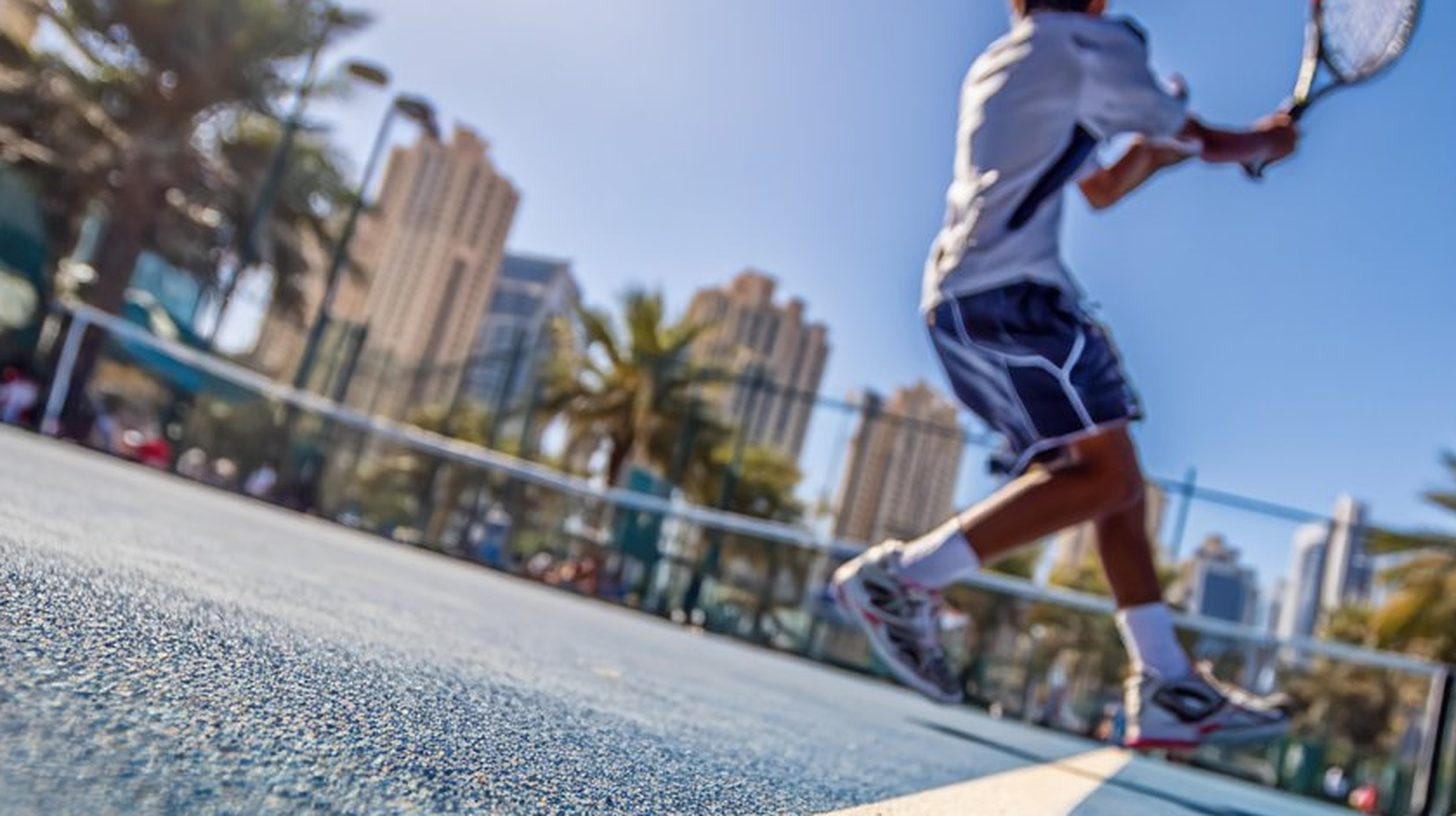 Junior tennis player training on court at a UAE tennis academy